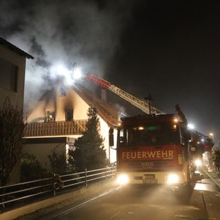 Feuerwehrleute löschen über eine Drehleiter Flammen in einem Einfamilienhaus. Bei einem Brand im Ulmer Stadtteil Jungingen ist ein Mensch ums Leben gekommen. Die Feuerwehr barg einen Toten. 