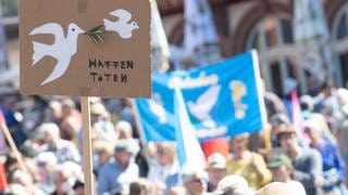"Waffen töten" steht während der Abschlusskundgebung der Ostermärsche des "Netzwerks Friedenskooperative" auf einem Schild.