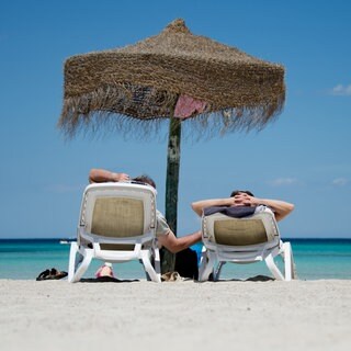 Deutsche Urlauber liegen an einem Strand im Norden der Mittelmeerinsel Mallorca.