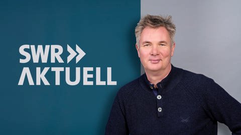 Gerald Pinkenburg steht vor dem Logo von SWR Aktuell.