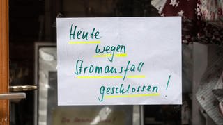 Im Fenster eines Geschäfts hängt ein Zettel "Heute wegen Stromausfall geschlossen"