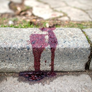 Nach einem Messerangriff auf eine Frau klebt Blut an einem Bordstein