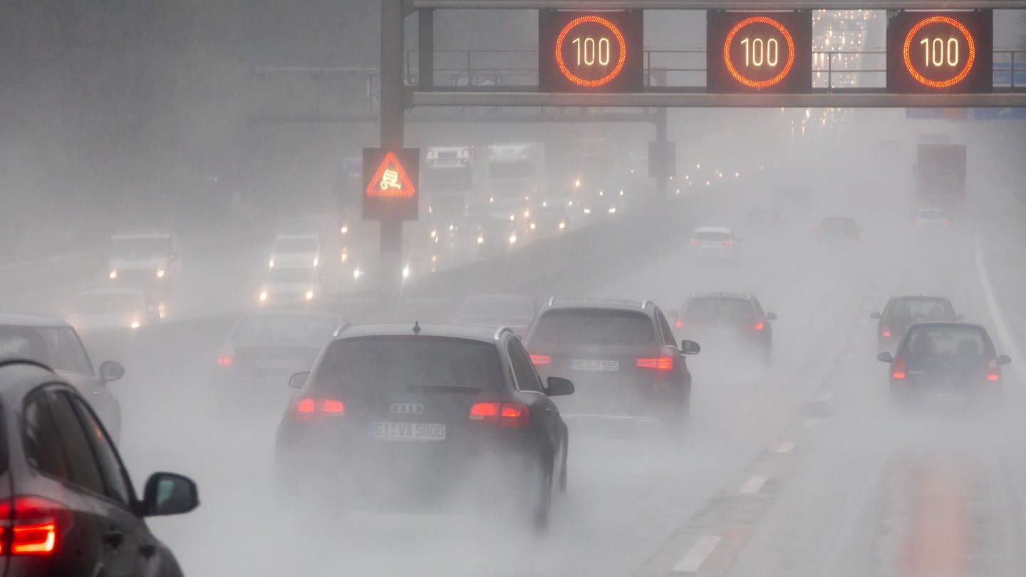 Hessen, Friedberg: Bei starkem Regen sind Fahrzeuge auf der Autobahn 5 unterwegs. Die zuschaltbaren Verkehrsschilder beschränken die Geschwindigkeit und warnen vor Schleudergefahr.