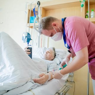 Alexander Plessow, Leitender Krankenpfleger auf der Viszeralchirurgie-Station, spritzt bei einem Patientenrundgang auf der Viszeralchirurgie-Station des Krankenhauses Havelhöhe Natriumchloridlösung in einen Zugang eines Patienten.