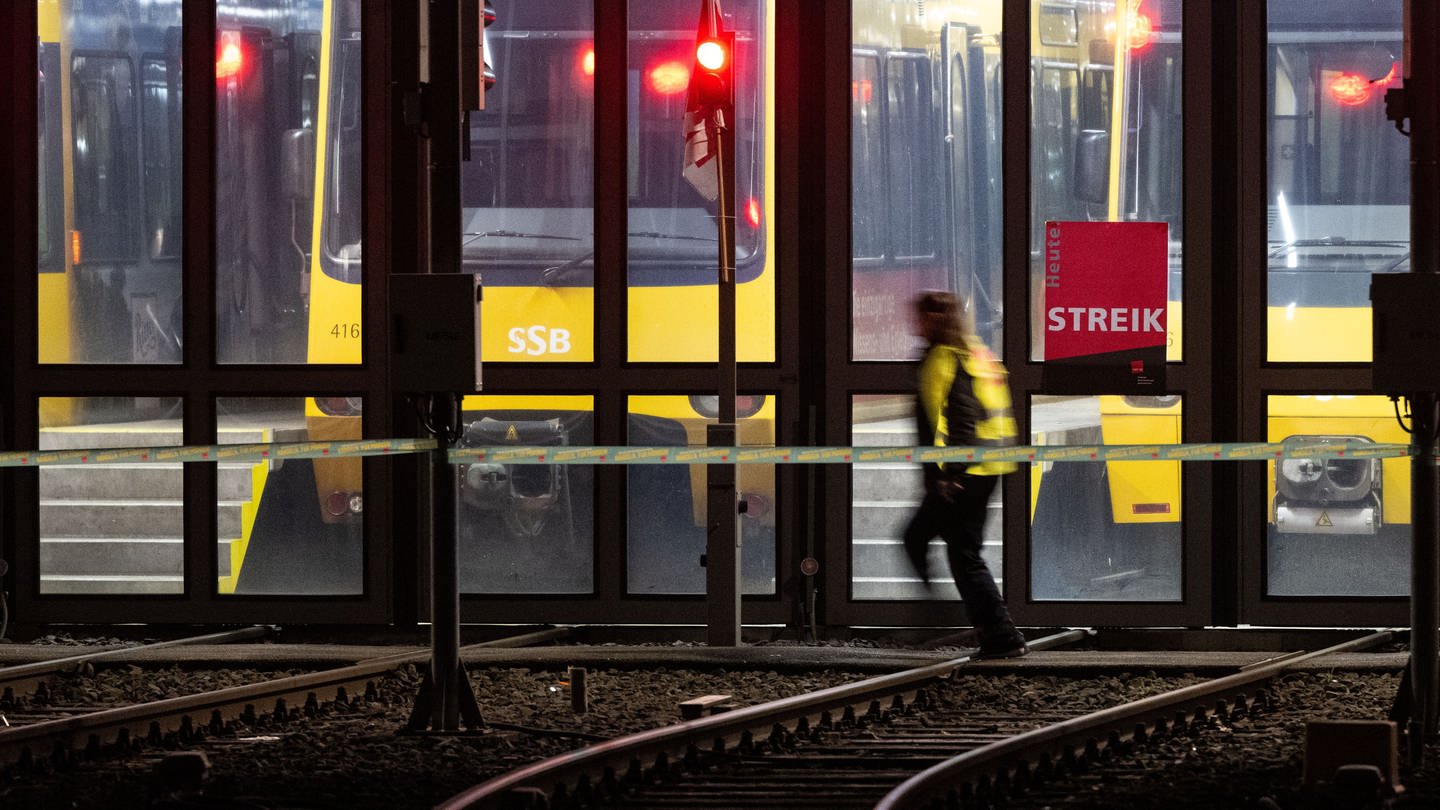 Eine Teilnehmerin eines Warnstreiks geht vor einem Stadtbahndepot der Stuttgarter Straßenbahnen AG (SSB).