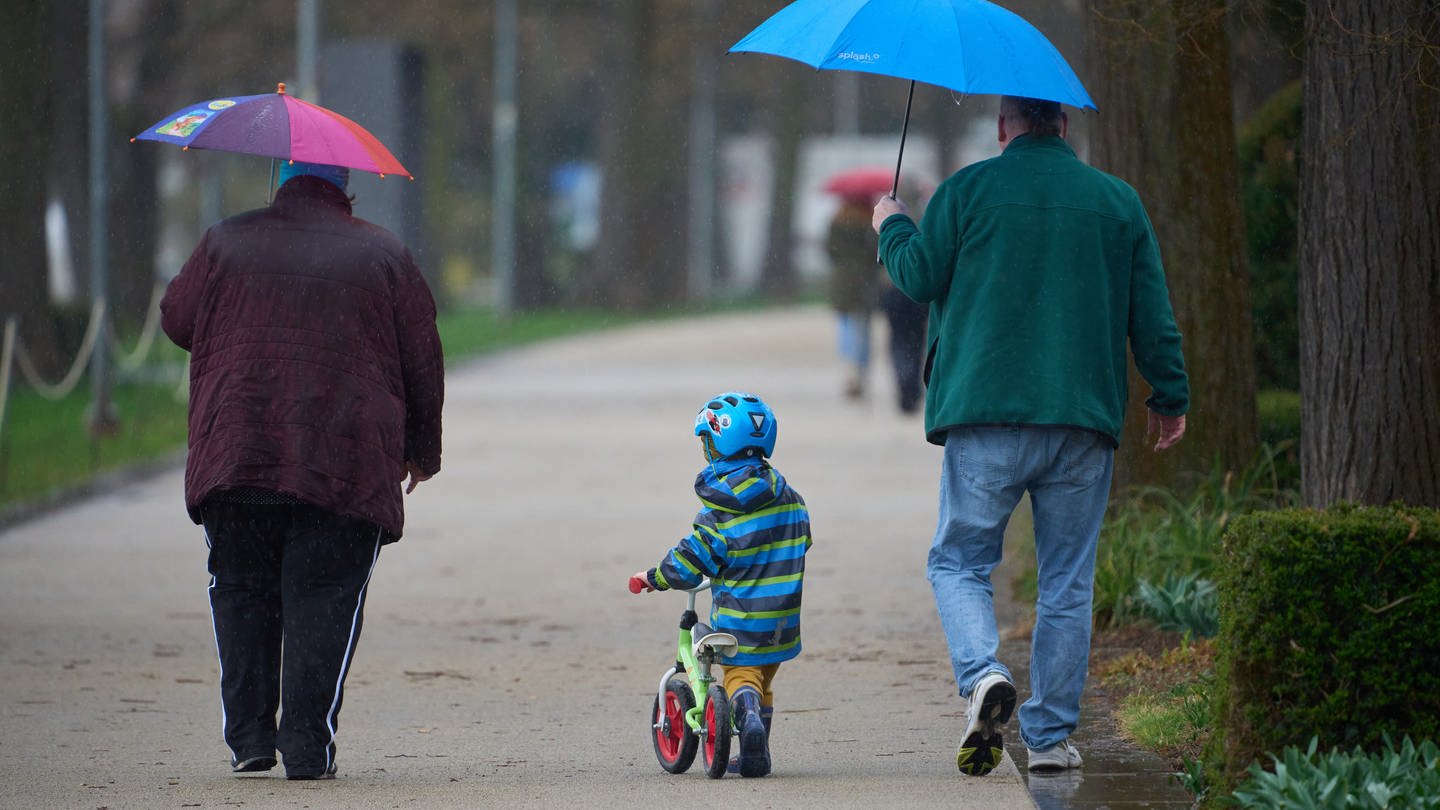 Spaziergänger laufen bei Regenwetter durch die Koblenzer Rheinanlagen