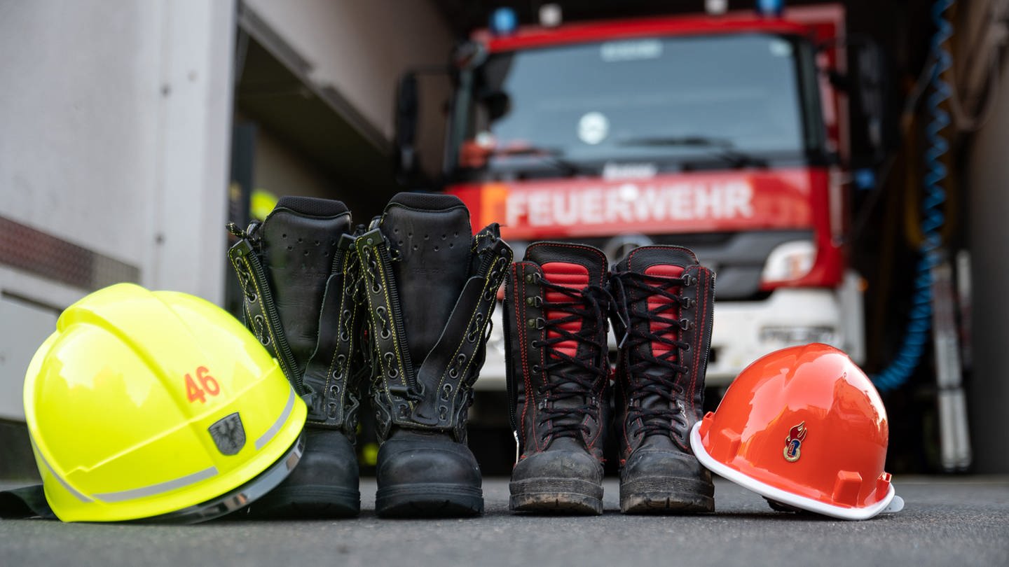Feuerwehrstiefel und Helme vor einem Feuerwehrfahrzeug - in Kaiserslautern zieht es viele Kinder und Jugendliche zur Feuerwehr