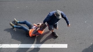 Ein Autofahrer schleift einen Demonstranten über eine Straße