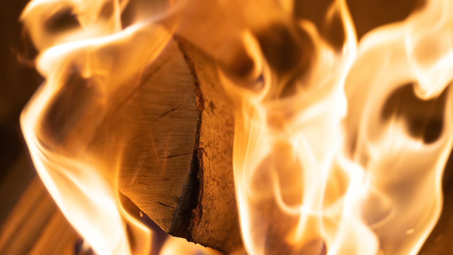 Holzscheite brennen in einem Ofen, der dazu genutzt wird, eine Wohnung zu heizen. Die Preise für Brennholz sind wieder auf dem Niveau, bevor der Ukraine-Krieg begonnen hatte. 2022 waren sie stark gestiegen.
