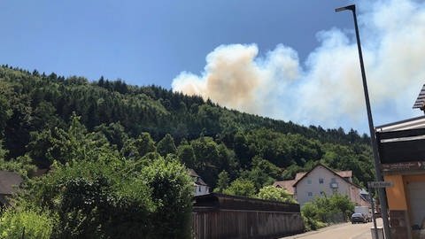 In Rodalben bei Pirmasens steigt Rauch über einem Waldgebiet auf. Aufgrund eines Waldbrandes bei Pirmasens in der Westpfalz haben Bewohner ihre Häuser verlassen müssen. Es wurde eine Sammelstelle für die Menschen in einer Schulhalle eingerichtet, wie die Polizei in Pirmasens am Dienstag mitteilte.