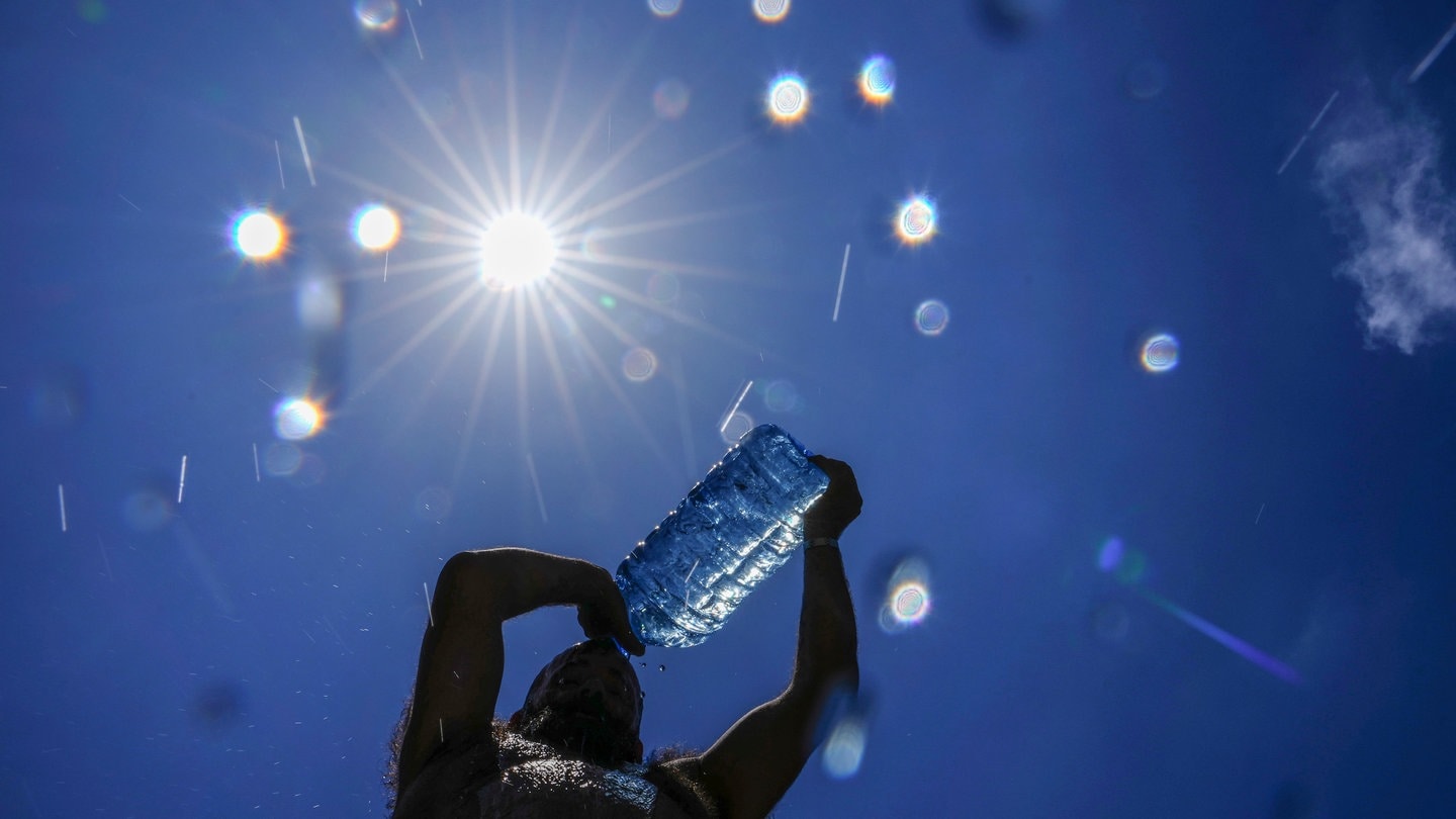 Ein Mann gießt sich bei extremer Hitze Wasser über den Kopf