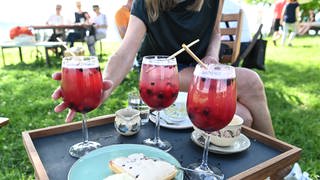 Eine Frau greift auf dem Hochwart auf der Insel Reichenau nach ihrem alkoholfreien Cocktail