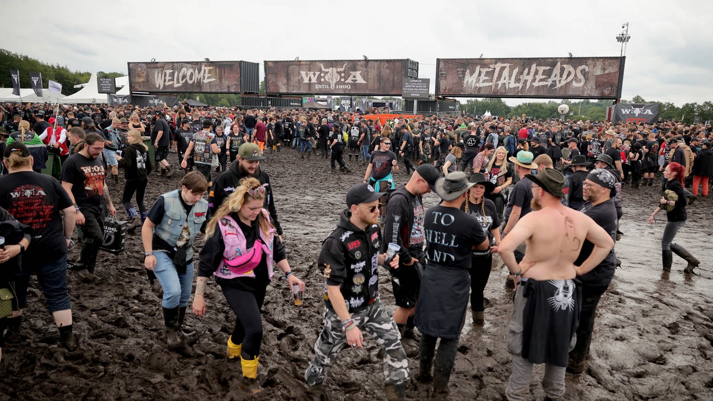 Metal-Fans laufen über das schlammige Gelände des Wacken-Festivals