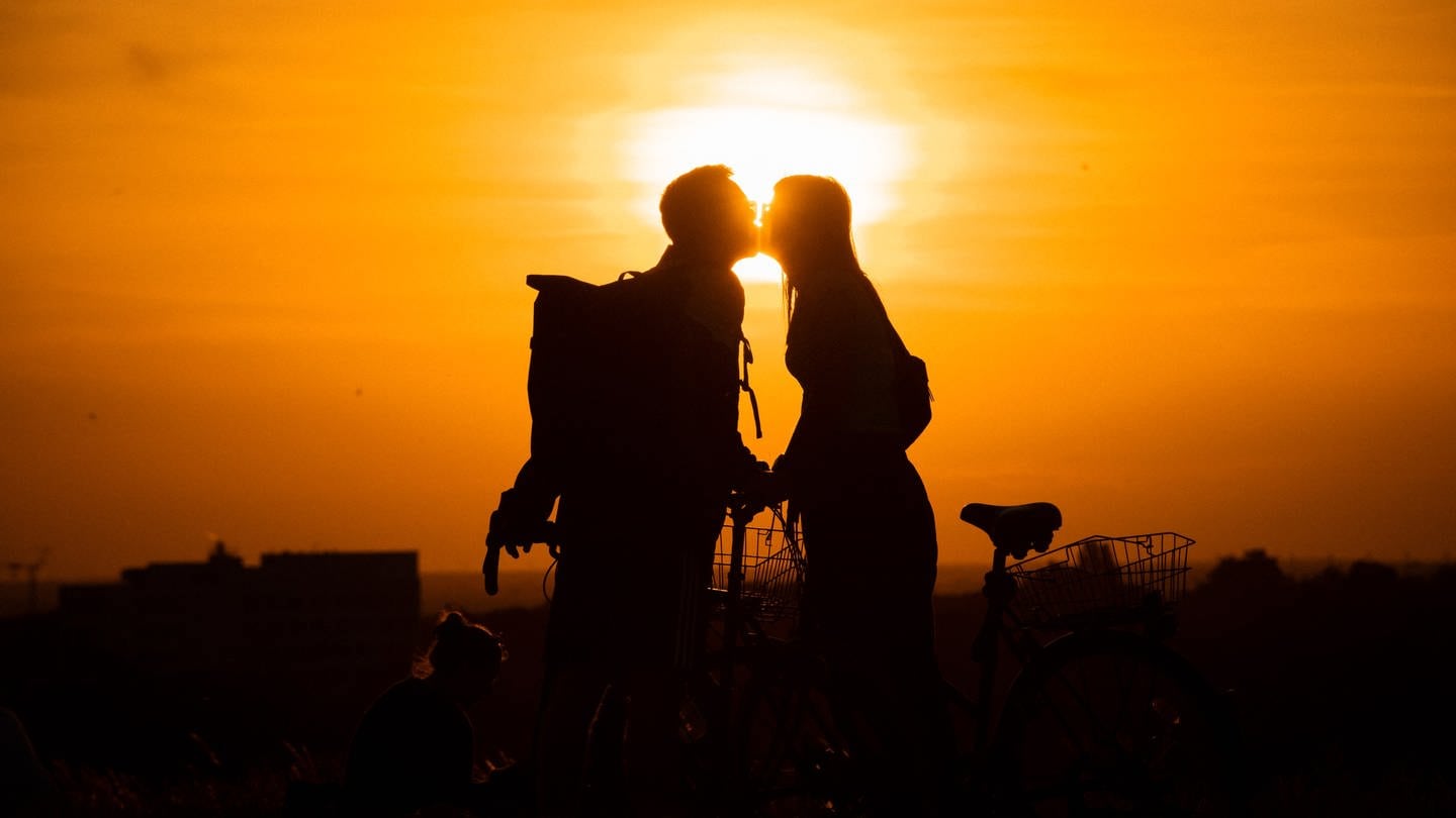 Im Licht der untergehenden Sonne küssen sich eine Frau und ein Mann auf dem Drachenberg.