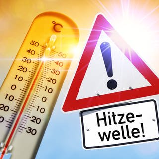 Fotomontage: Schild mit Aufschrift "Hitzewelle" vor brennender Sonne und Thermometer.