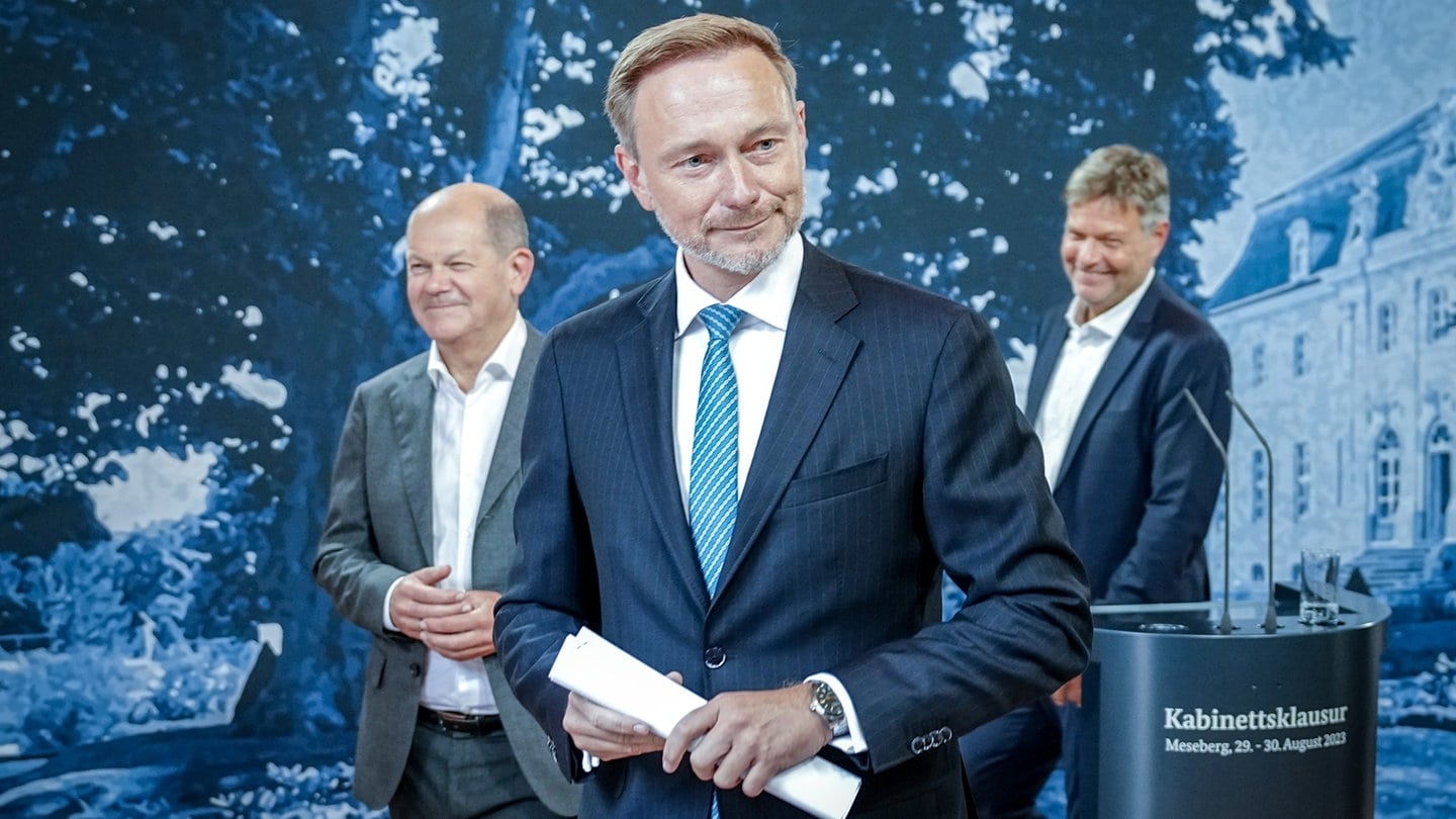 Finanzminister Lindner im Vordergrund, Bundeskanzler Scholz und Wirtschaftsminister Habeck im Hintergrund bei einem Pressestatement zur Kabinettskalusur in Meseberg