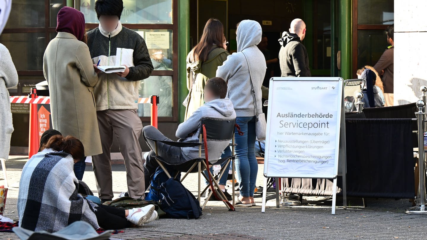 Menschen warten schon Stunden vor der Öffnung vor dem Eingang der Stuttgarter Ausländerbehörde. Die Wartezeiten sind in den letzten Monaten drastisch angestiegen.
