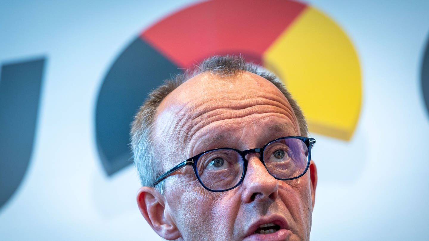 CDU-Chef Friedrich Merz, über seinem Kopf -bogenförmig- die Deutschlandfarben Scwharz, Rot und Gold