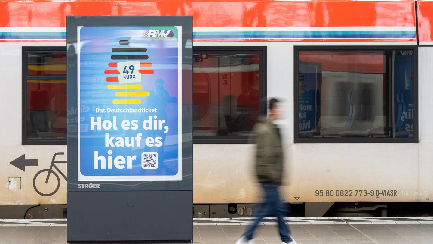 Die Werbung für das Deutschlandticket ist an einem Bahnsteig vor einer Bahn des ÖPNV zu sehen.