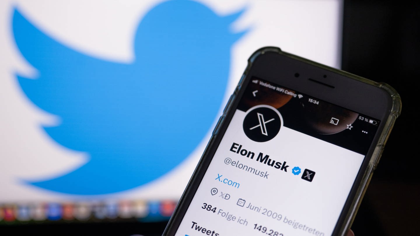 Ein Smartphone zeigt den X-Account von Elon Musk vor einem alten Twitter-Logo