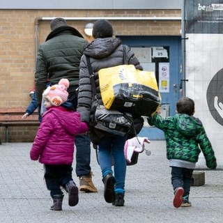 Ein Flüchtling geht mit seiner Familie auf dem Gelände der Erstaufnahmeeinrichtung des Landesamtes für Flüchtlingsangelegenheiten.