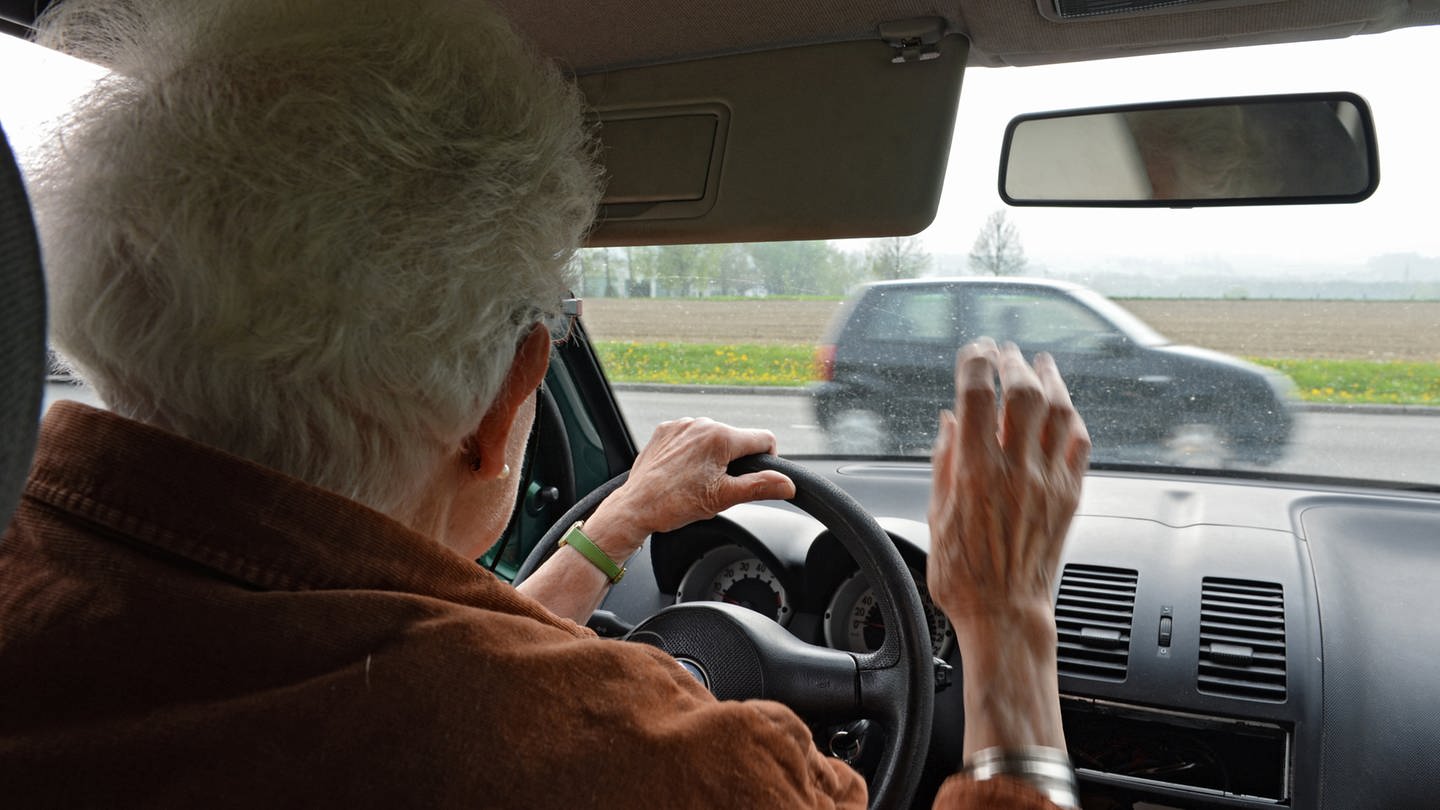 Eine ältere Frau im Auto sieht ein anderes Fahrzeug direkt vor sich.
