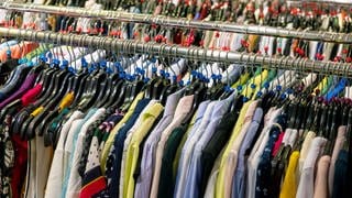 Textilien als Massenware: Verschiedenfarbige Hemden, Blusen und Westen werden im Einzelhandel als Massenware auf endlosen Kleiderstangen angeboten.