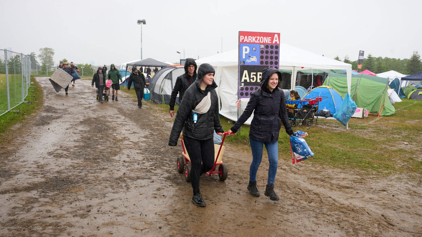 Im strömenden Regen reisen Rockfans auf dem Campinggelände des Festivals 