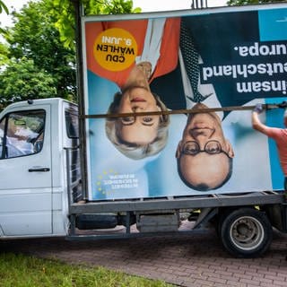 Auf einen Transporter wird ein Wahlplakat der CDU nach dem Abbau verladen.