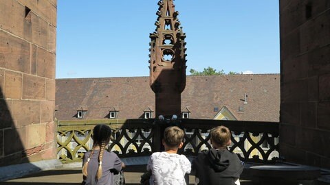 Schulkinder sitzen auf einem Zwischengeschoss des Freiburger Münsters