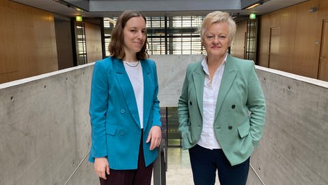 Korrespondentin Eva Huber und Renate Künast stehen in der Halle im ARD-Hauptstadtstudio nebeneinander und schauen in die Kamera