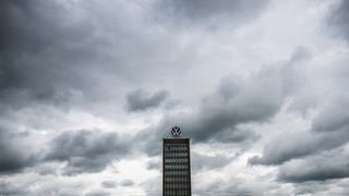 Hochhaus mit VW-Emblem umgeben von schwarzen Wolken