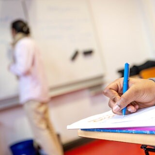 Nahaufnahme Hand: Schüler macht sich im Unterricht Notizen