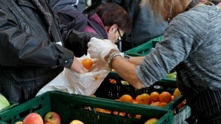 Ehrenamtliche Mitarbeiter der Tafel verteilen an Nutzer der Einrichtung Lebensmittel.