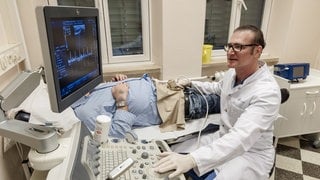 Ein Urologe untersucht den Penis eines Patienten mit einem Ultraschallgerät.