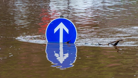 Ein Verkehrsschild steht im Hochwasser und wird vom stark gestiegenen Wasserspiegel fast verdeckt