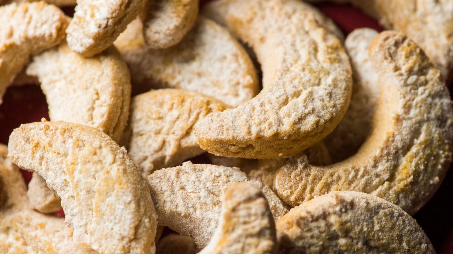 Vanillekipferl liegen auf einem Haufen auf rotem Untergrund