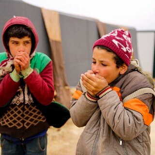 Zwei Kinder wärmen sich die Hände in einem Flüchtlingslager im Nordwesten Syriens (Archiv, 2022)