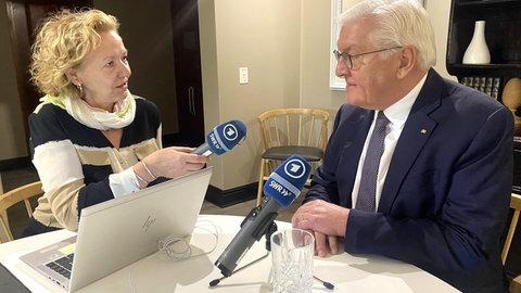 Korrespondentin Evi Seibert und Frank-Walter Steinmeier sitzen sich beim Interview an einem Tisch mit ARD-Mikrofonen gegenüber