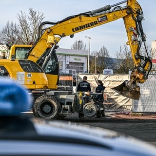 Ein Bagger steht nach einer Zerstörungsfahrt neben einem Autohaus in Tauberbischofsheim . Nach der zerstörerischen Baggerfahrt und tödlichen Polizeischüssen auf den Fahrer im Nordosten Baden-Württembergs laufen die Ermittlungen zu dem Geschehen.