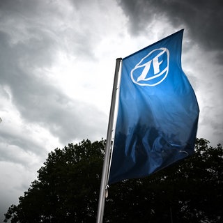 Eine Fahne mit dem Logo der ZF-Friedrichshafen AG weht vor dem ZF-Forum in Friedrichshafen, während sich im Hintergrund ein Gewitter zusammenbraut