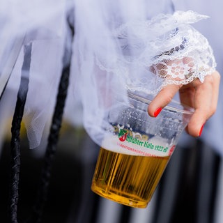 Nahaufnahme Hand hält Plastikbecher mit Bier im Karneval