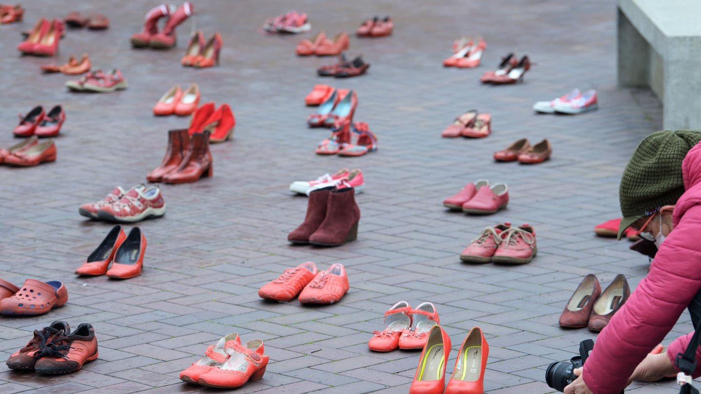 Eine Frau fotografiert am „Internationalen Tag gegen Gewalt an Frauen“ im Innenhof des Landtages rote Frauenschuhe. Mit 117 Paar Schuhen soll auf 117 Opfer von Femiziden in der Partnerschaft im letzten Jahr aufmerksam gemacht werden. Die mit dem Hissen einer Fahne verbundene Aktion ist Teil der UN-Women Kampagne 