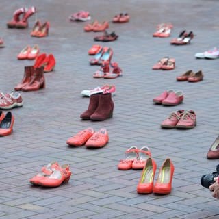 Eine Frau fotografiert am „Internationalen Tag gegen Gewalt an Frauen“ im Innenhof des Landtages rote Frauenschuhe. Mit 117 Paar Schuhen soll auf 117 Opfer von Femiziden in der Partnerschaft im letzten Jahr aufmerksam gemacht werden. Die mit dem Hissen einer Fahne verbundene Aktion ist Teil der UN-Women Kampagne "Orange the World"