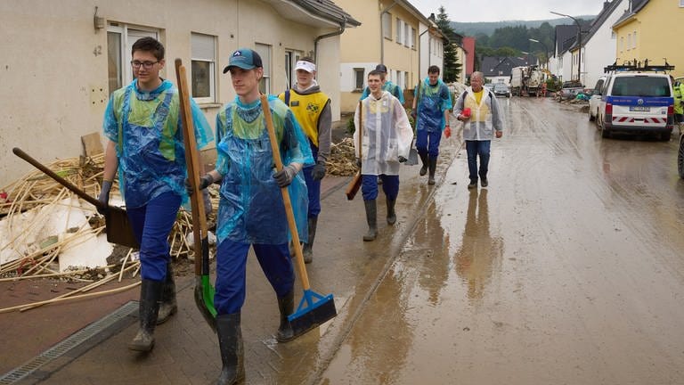 Eine Gruppe von Helfern aus den USA wechselt im strömenden Regen den Einsatzort. 