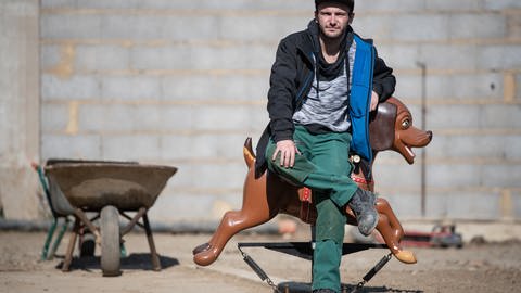 Der Schausteller Tim Himmes sitzt inmitten seiner Haus-Baustelle auf einem alten Karusselltier.