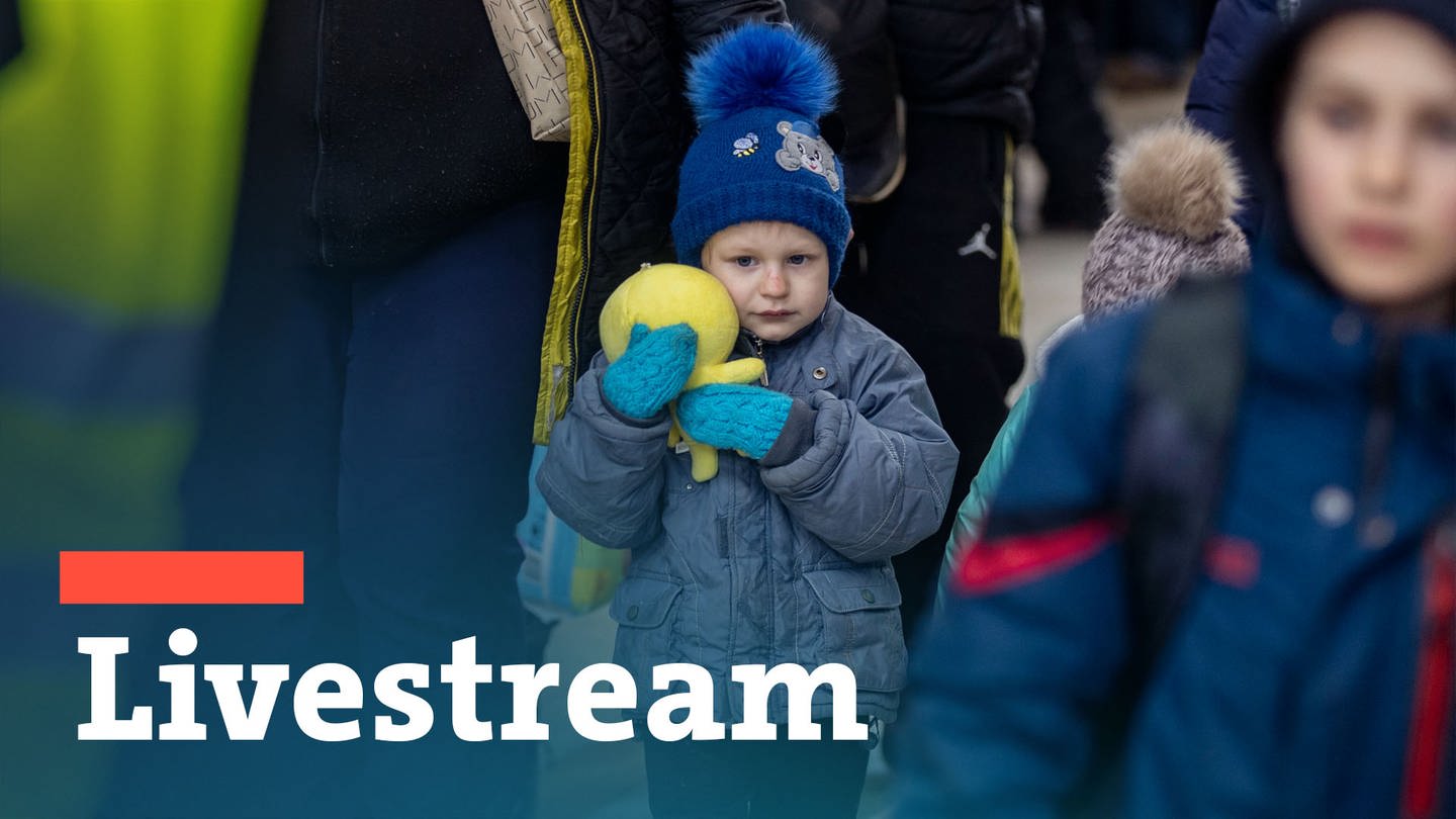 Ein kleiner Junge mit Mütze und Handschuhen mit seiner Mutter im Bahnhof in Przemysl, er drückt sein Stofftier ganz fest an seine Wange. Wie Flüchtlinge aus der Ukraine in Deutschland verteilt werden, ist Thema der MPK.