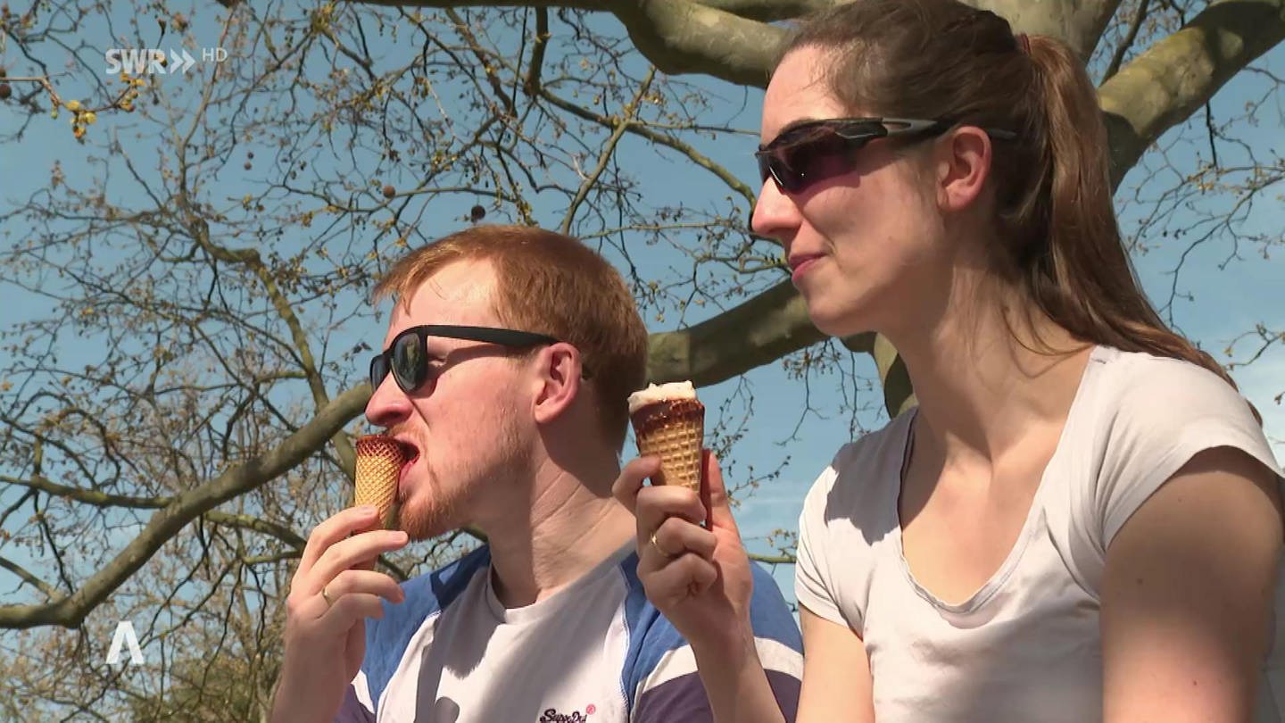 zwei Personen genießen den ersten Sommertag und essen Eis