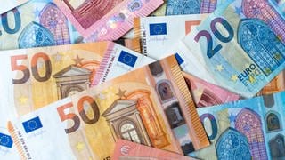 Zahlreiche Banknoten zu 10, 20 und 50 Euro liegen auf einem Tisch. 