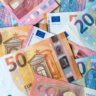 Zahlreiche Banknoten zu 10, 20 und 50 Euro liegen auf einem Tisch. 